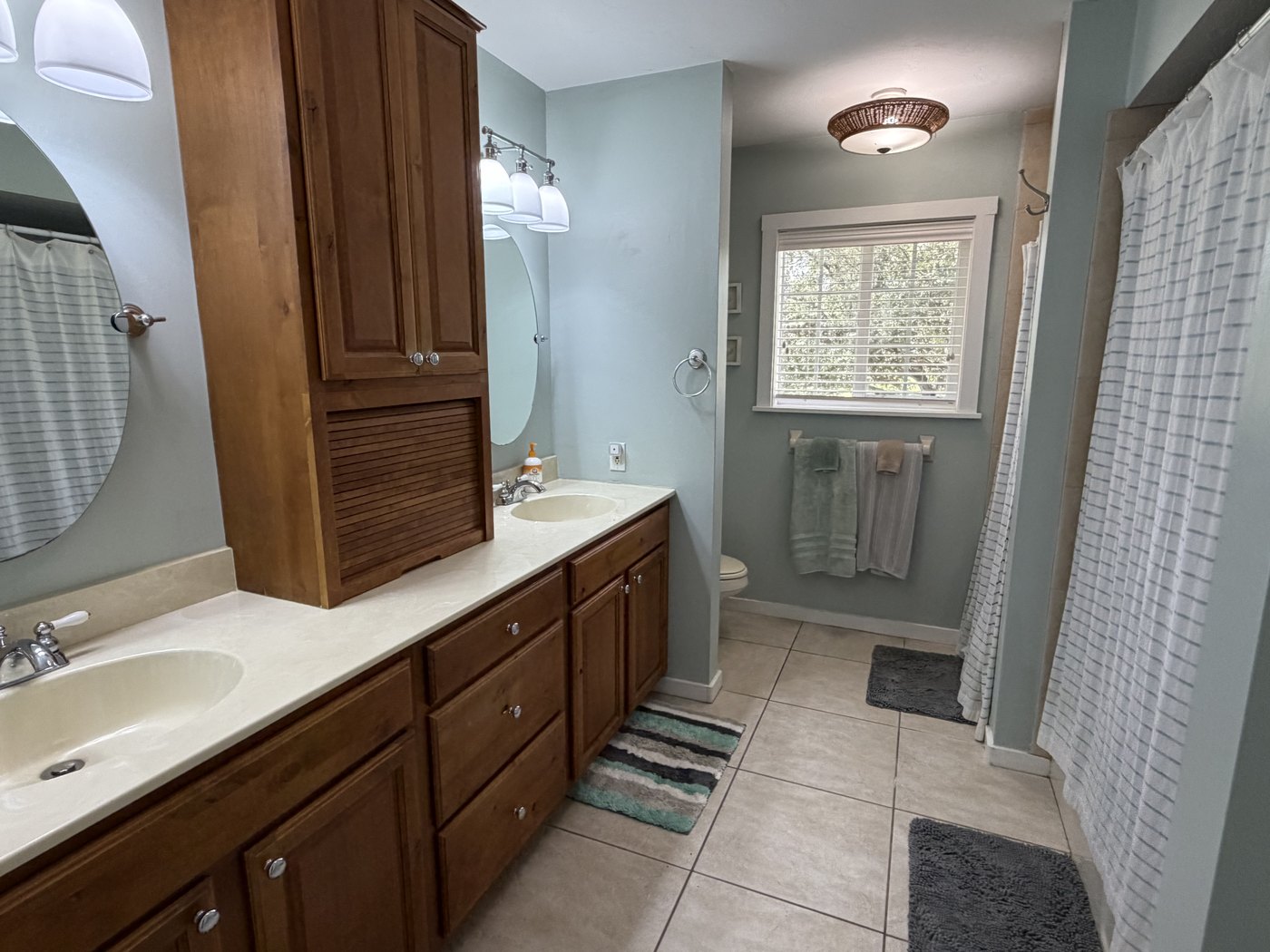 The master bathroom with a double vanity, separate shower and a window to the trees