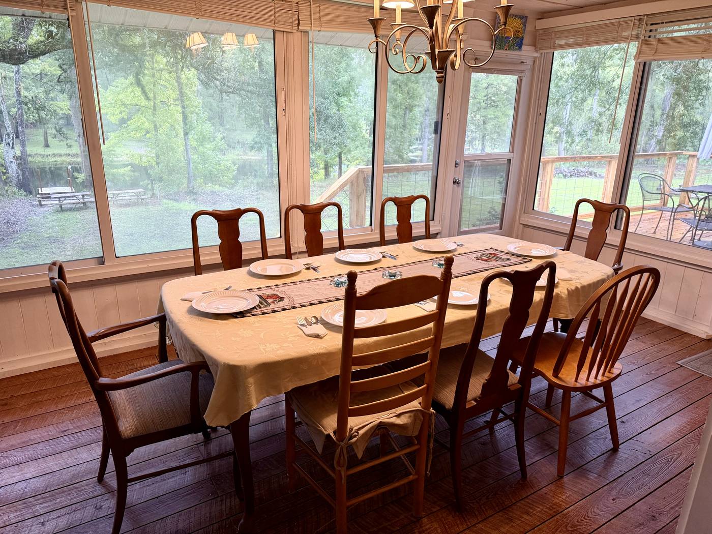 The Florida room dining table beneath walls of windows overlooking the river