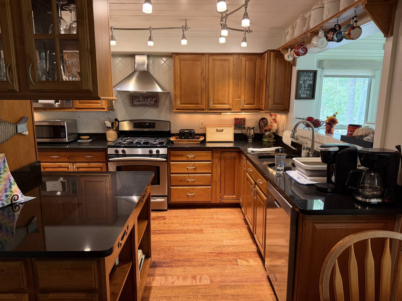 The full kitchen with gas range, stone counters and wood cabinetry
