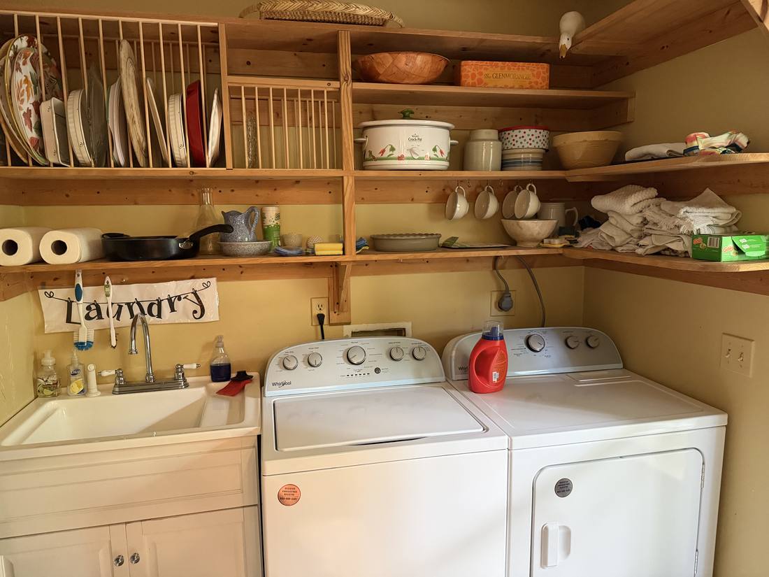 The laundry room with washer, dryer, deep sink and open shelving