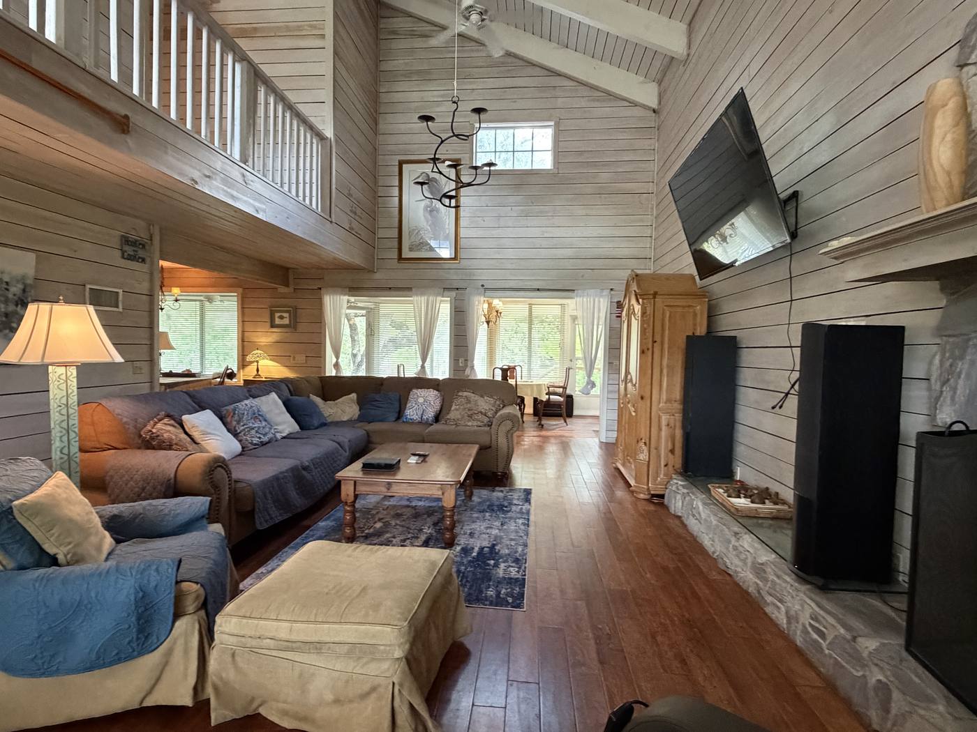 The cabin-style great room with soaring wood ceilings and a third-floor walkway above